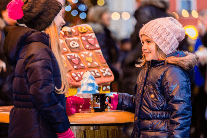 Two children exploring the holiday market event, browsing through festive stalls and decorations.