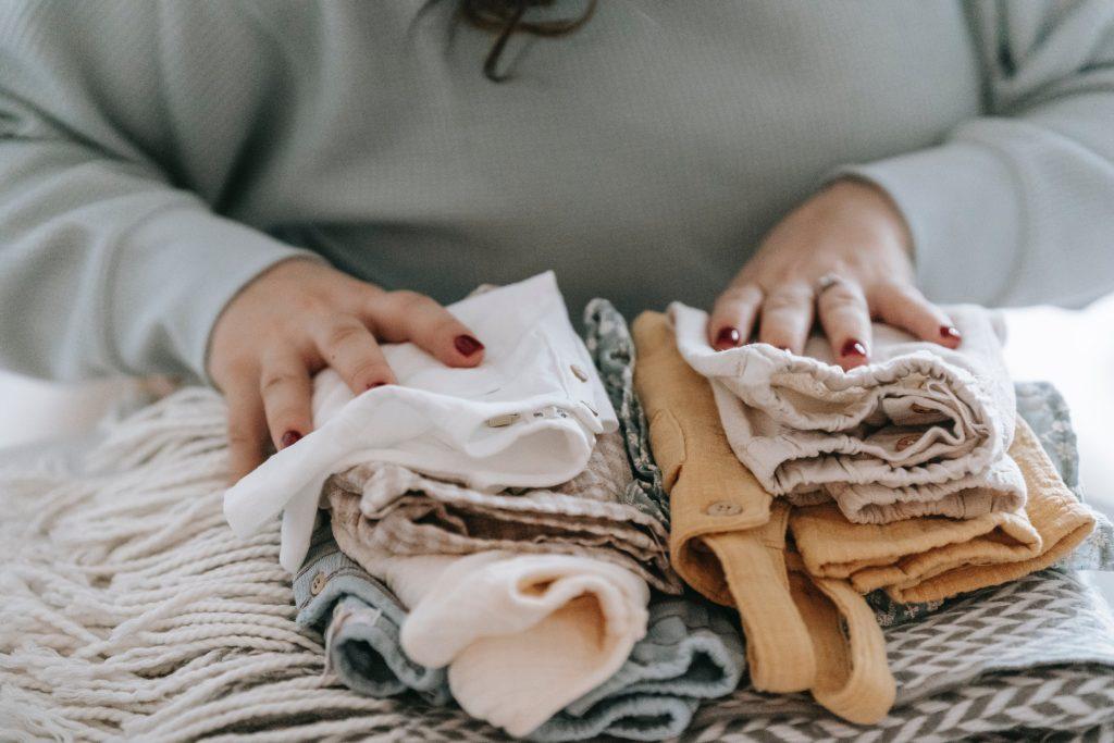 woman's hands on folded baby clothes