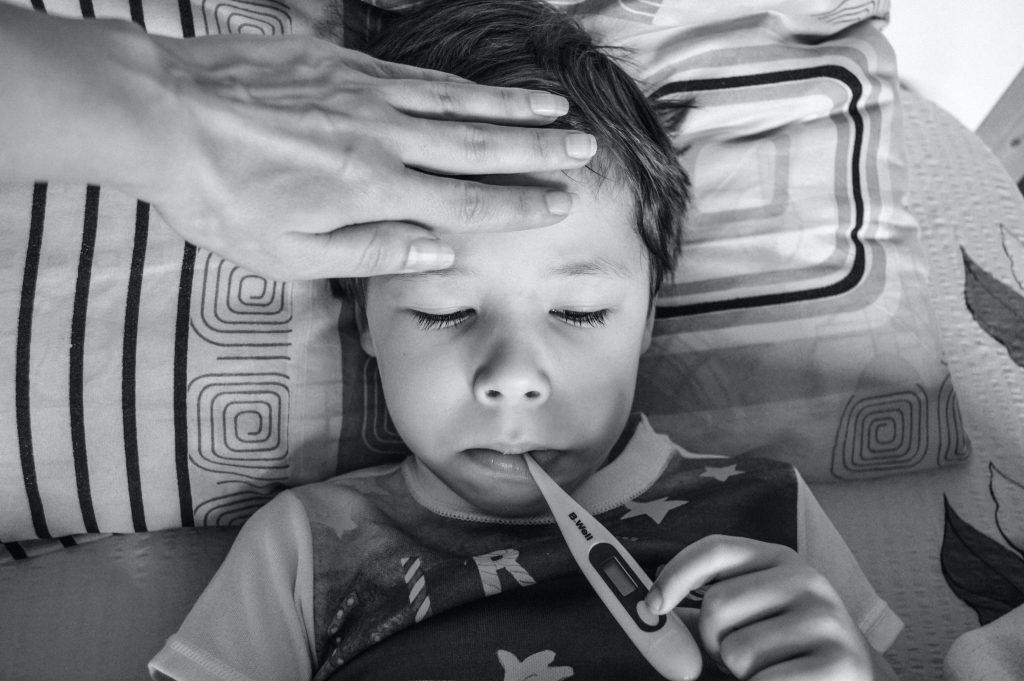 boy laying down with thermometer in his mouth