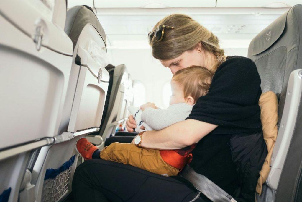 Woman holding baby while sitting in an airplane seat