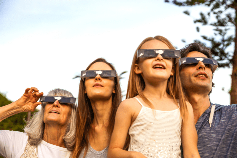 Family wearing solar eclipse glasses outdoors, solar eclipse cape cod