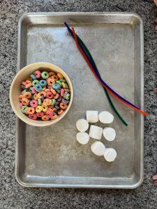froot loops, marshmallows, and pipe cleaners on a cookie tray