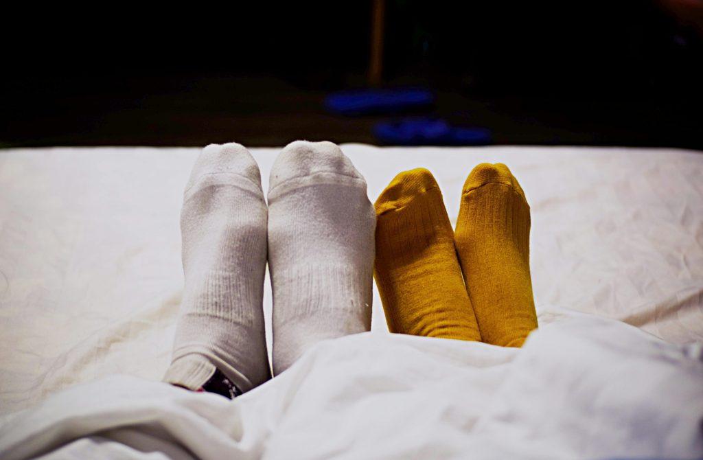 two pairs of feet with socks in bed, barriers to arousal
