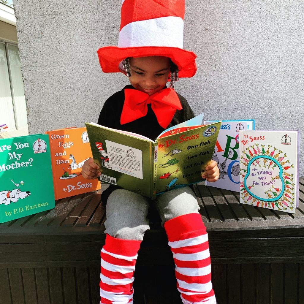 girl in dr. suess hat and socks reading dr. suess books, story times on cape cod